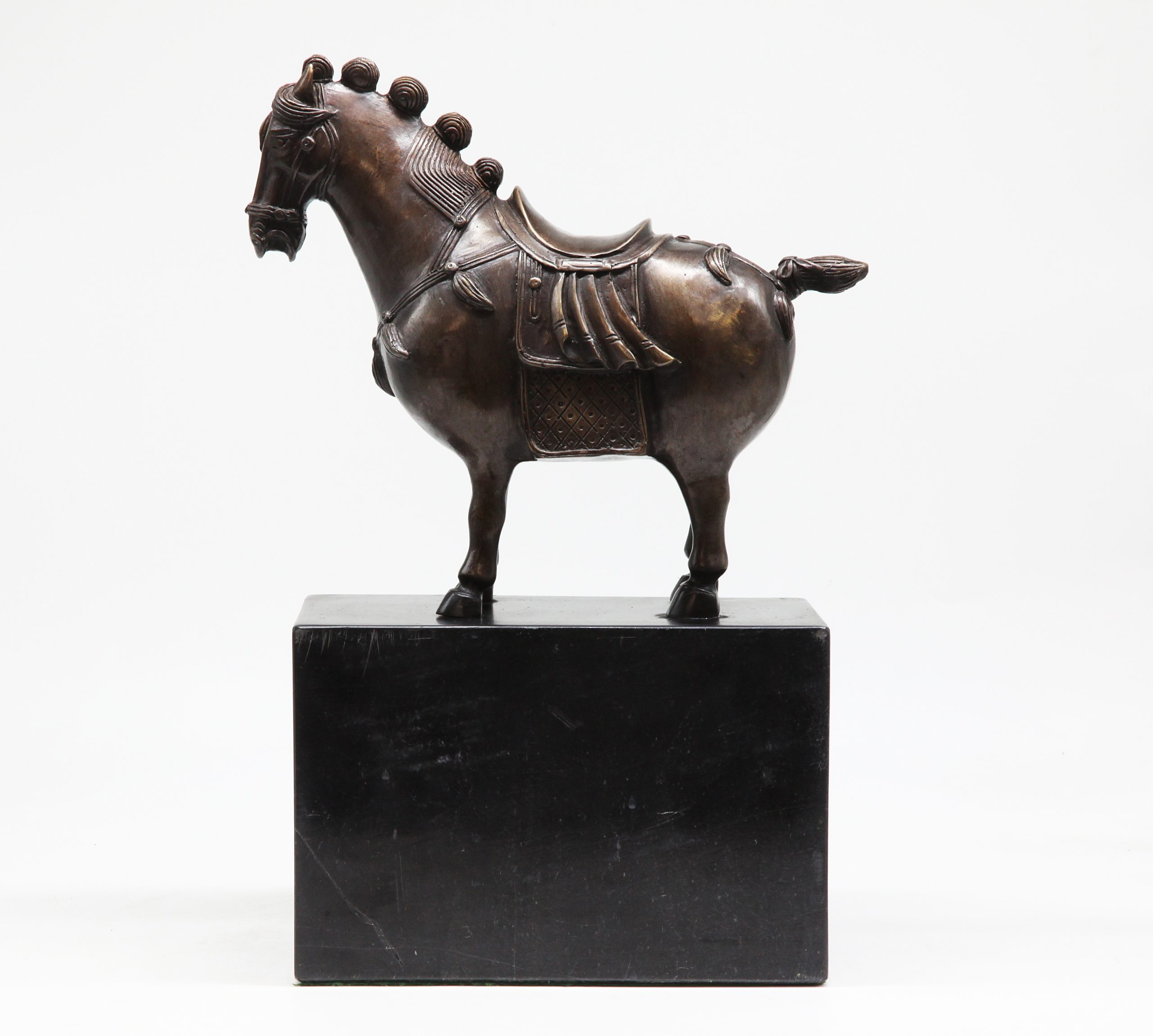 A figurative bronze sculpture of a decorative horse on top of a marble cube.