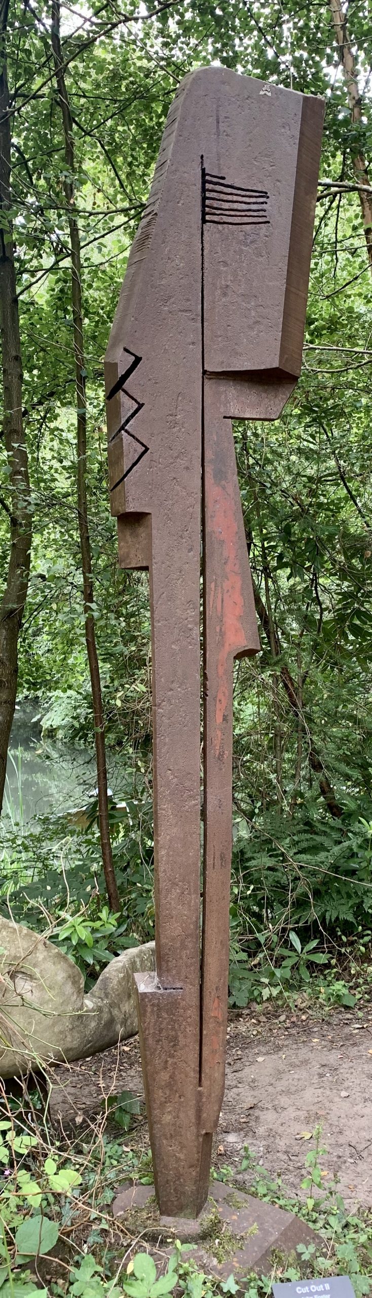 A abstract steel sculpture of a tall metal piece with slices in it.