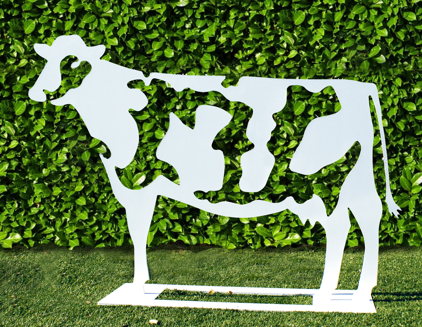 A pop art steel sculpture of a white cow standing with its fur markings cut out.