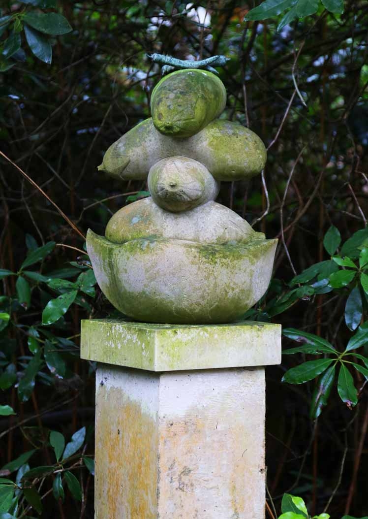 A contemporary stone and bronze sculpture of a collection of stacked vegetables.
