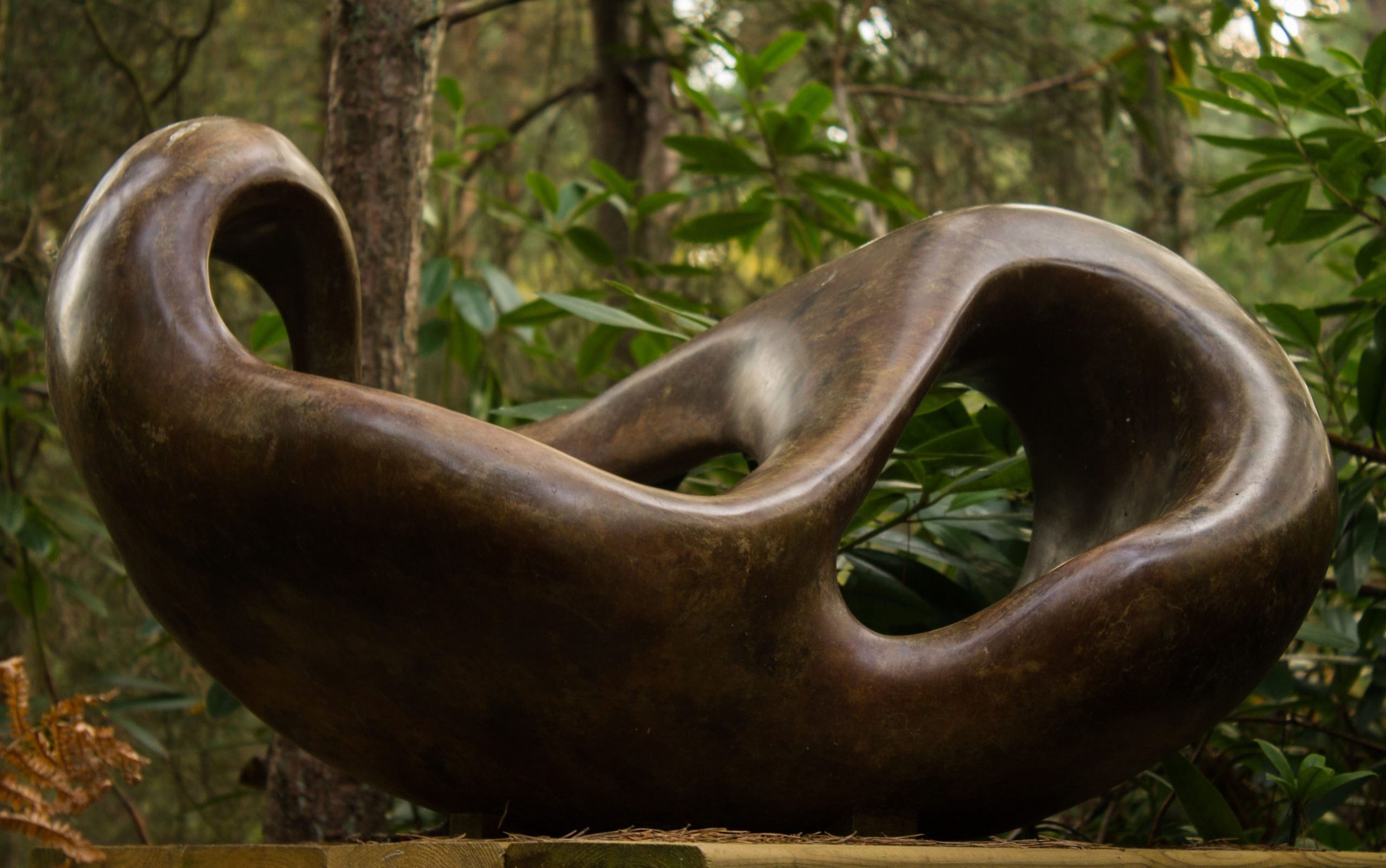 A figurative bronze sculpture of a shape reclining back in a relaxed manner.