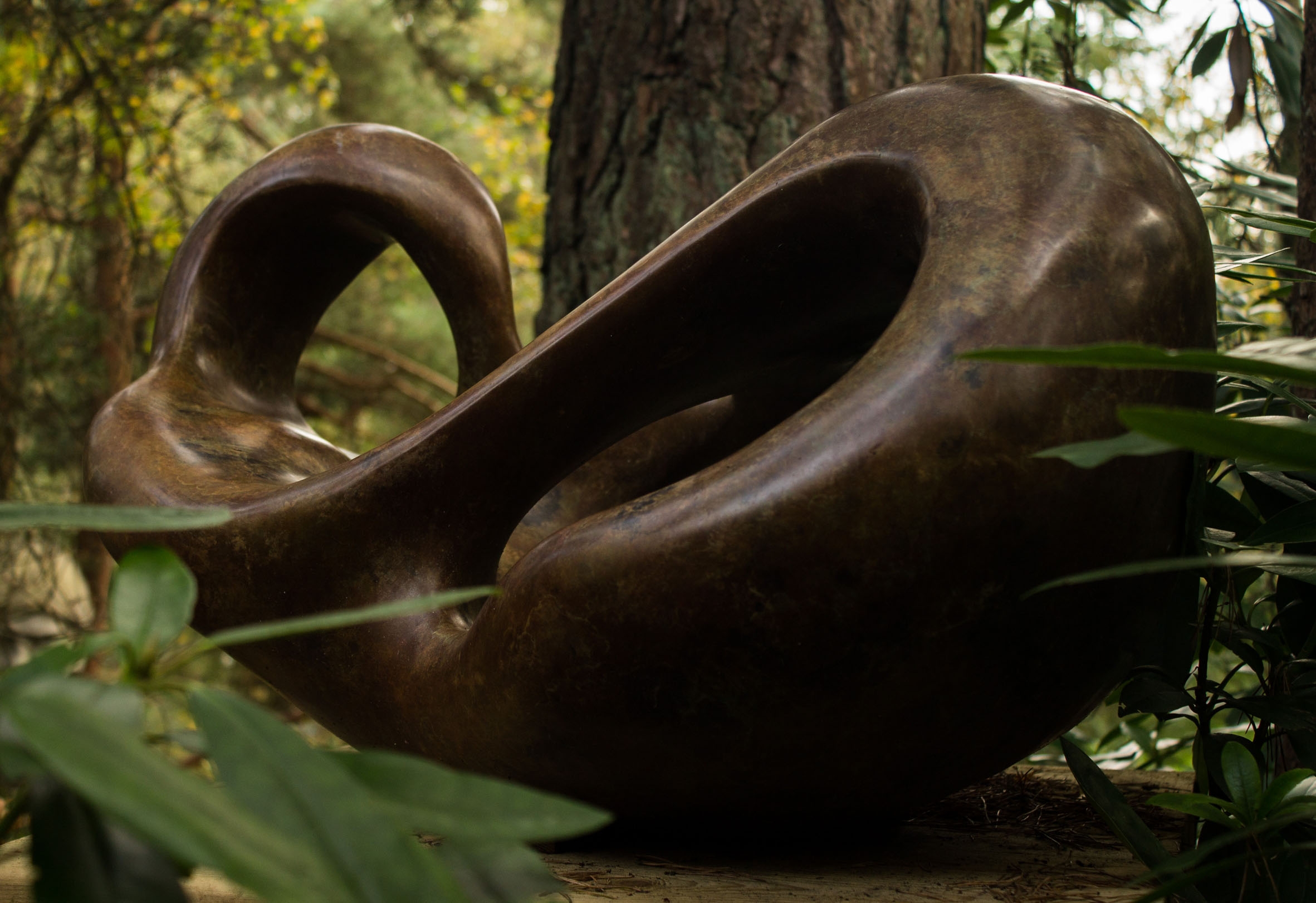 A figurative bronze sculpture of a shape reclining back in a relaxed manner.