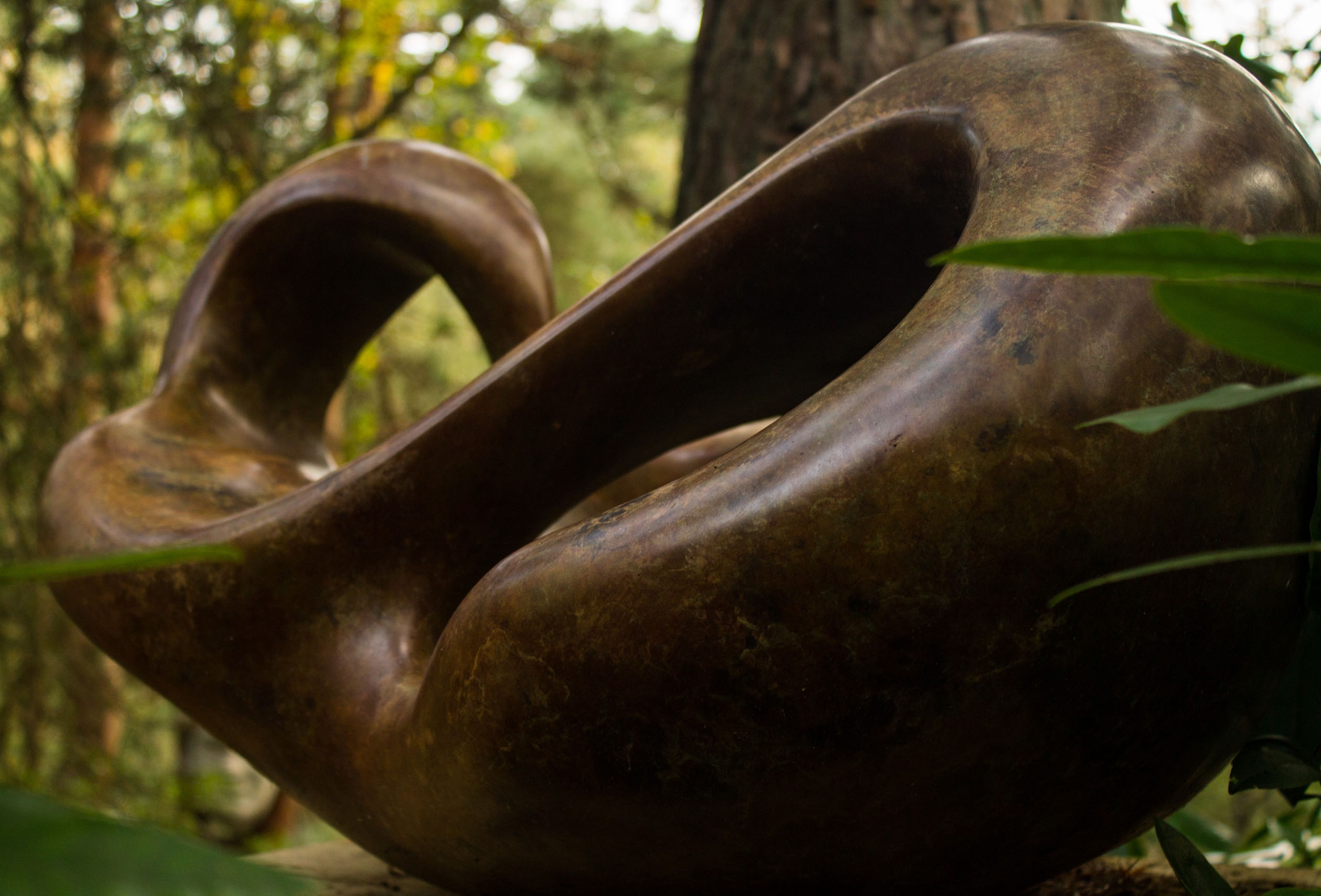 A figurative bronze sculpture of a shape reclining back in a relaxed manner.