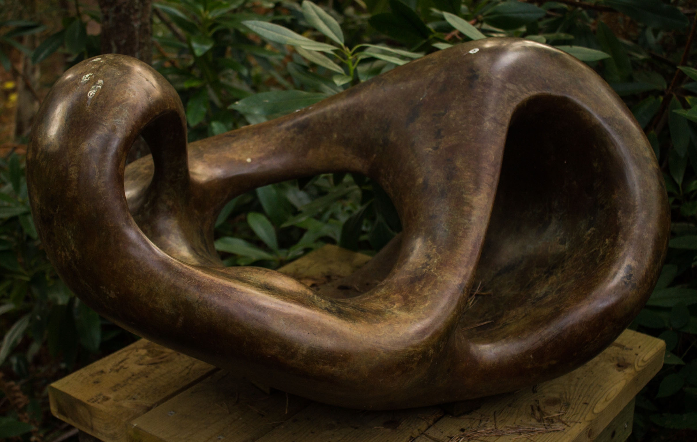 A figurative bronze sculpture of a shape reclining back in a relaxed manner.