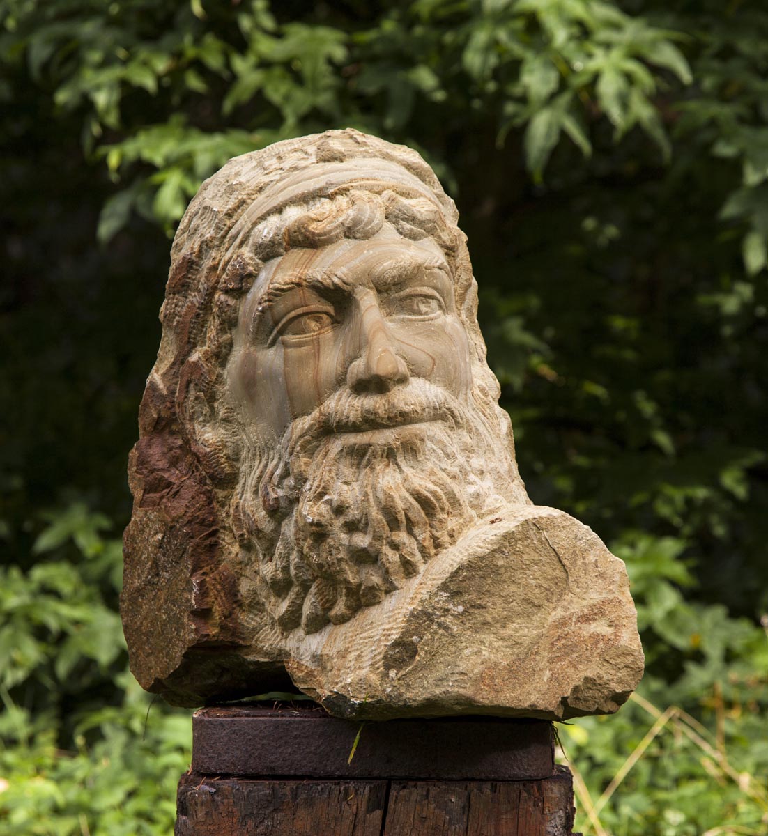 A figurative stone sculpture of a portrait of a man with a long beard.