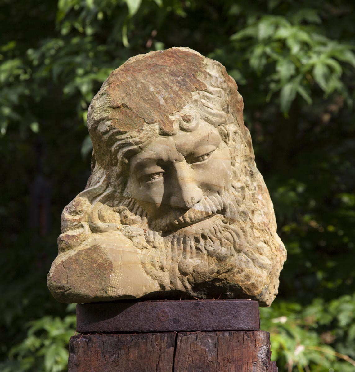A figurative stone sculpture of a portrait of a man with a long beard.
