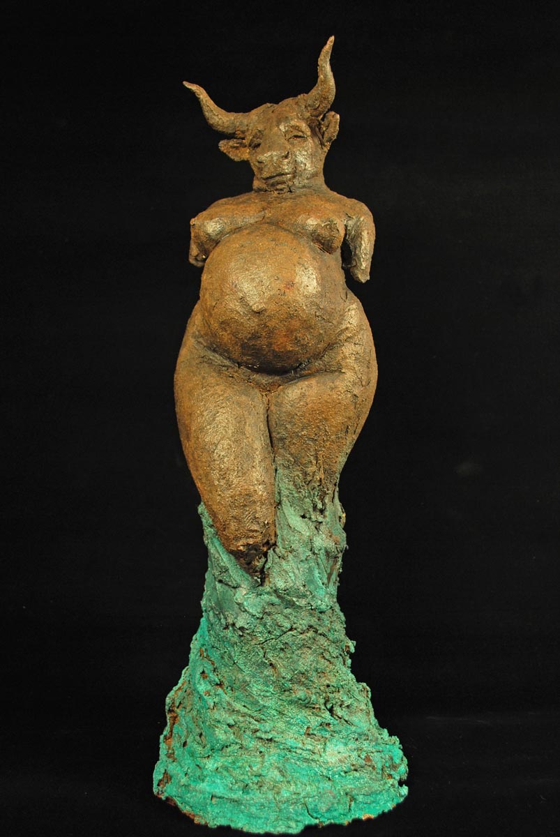 A figurative ceramic sculpture of a pregnant woman with a cows head posed to resemble Venus.