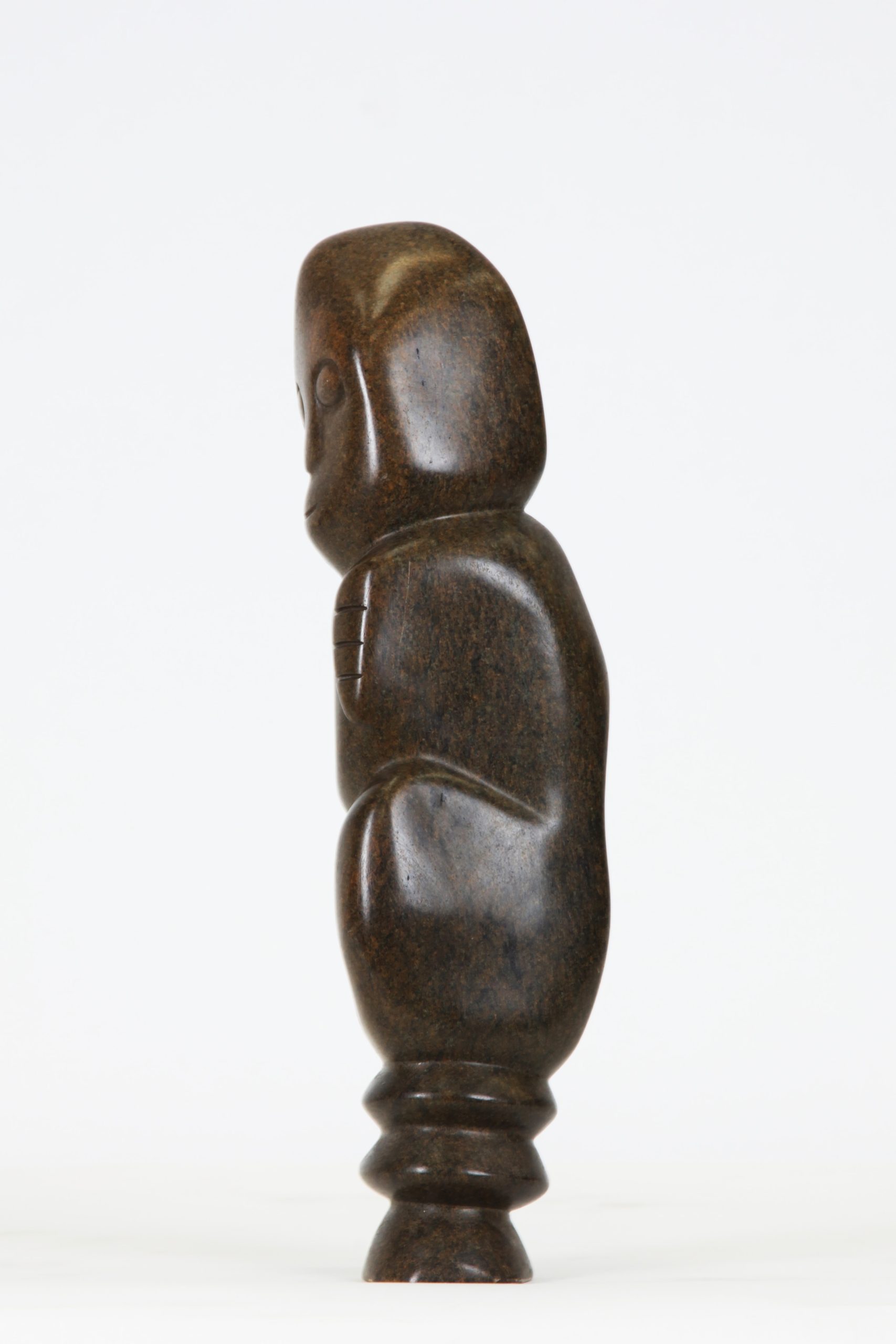 A Shona Serpentine stone sculpture of a person hunched over and hugging themselves.
