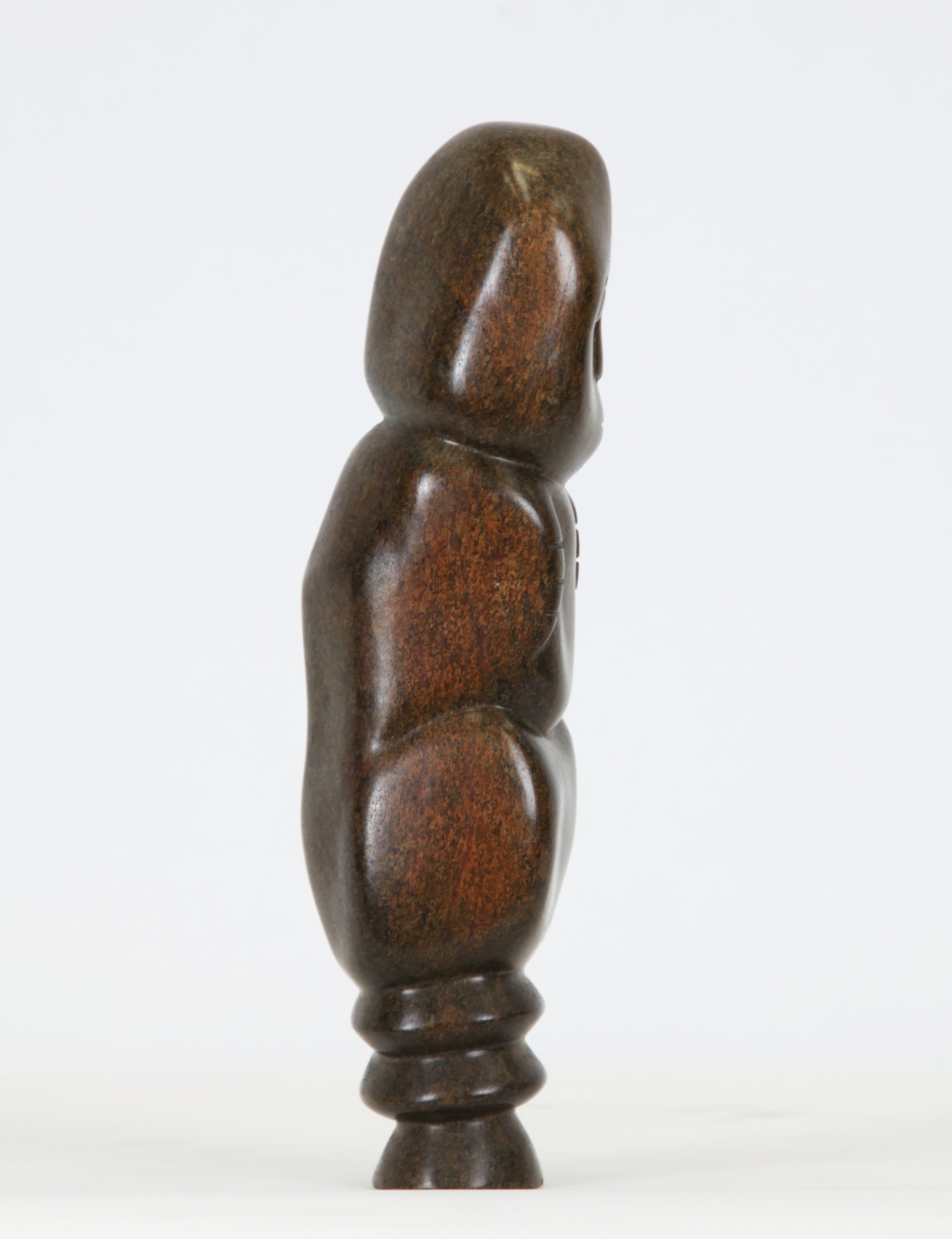 A Shona Serpentine stone sculpture of a person hunched over and hugging themselves.