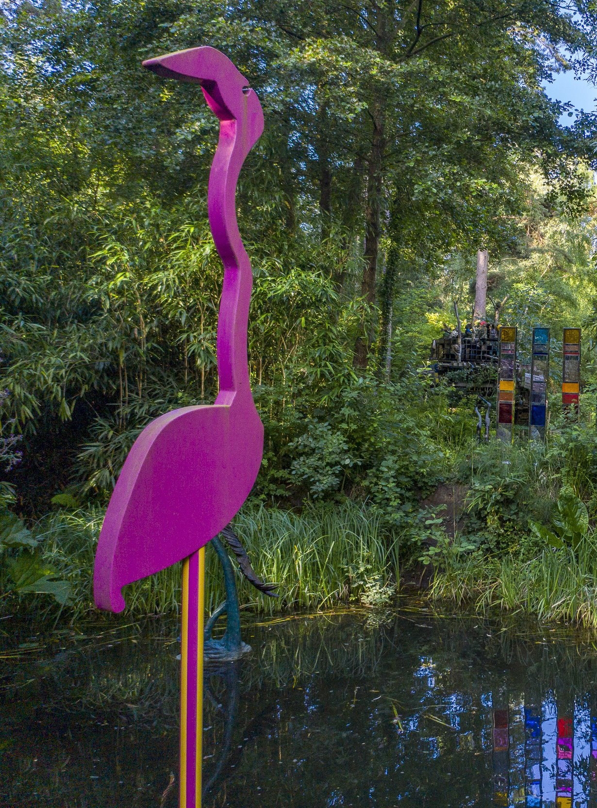 A figurative powder coated steel sculpture of a tall pink flamingo.
