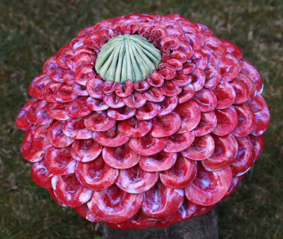 A floral stoneware sculpture of a abstract flower with a large plumage of pink petals.