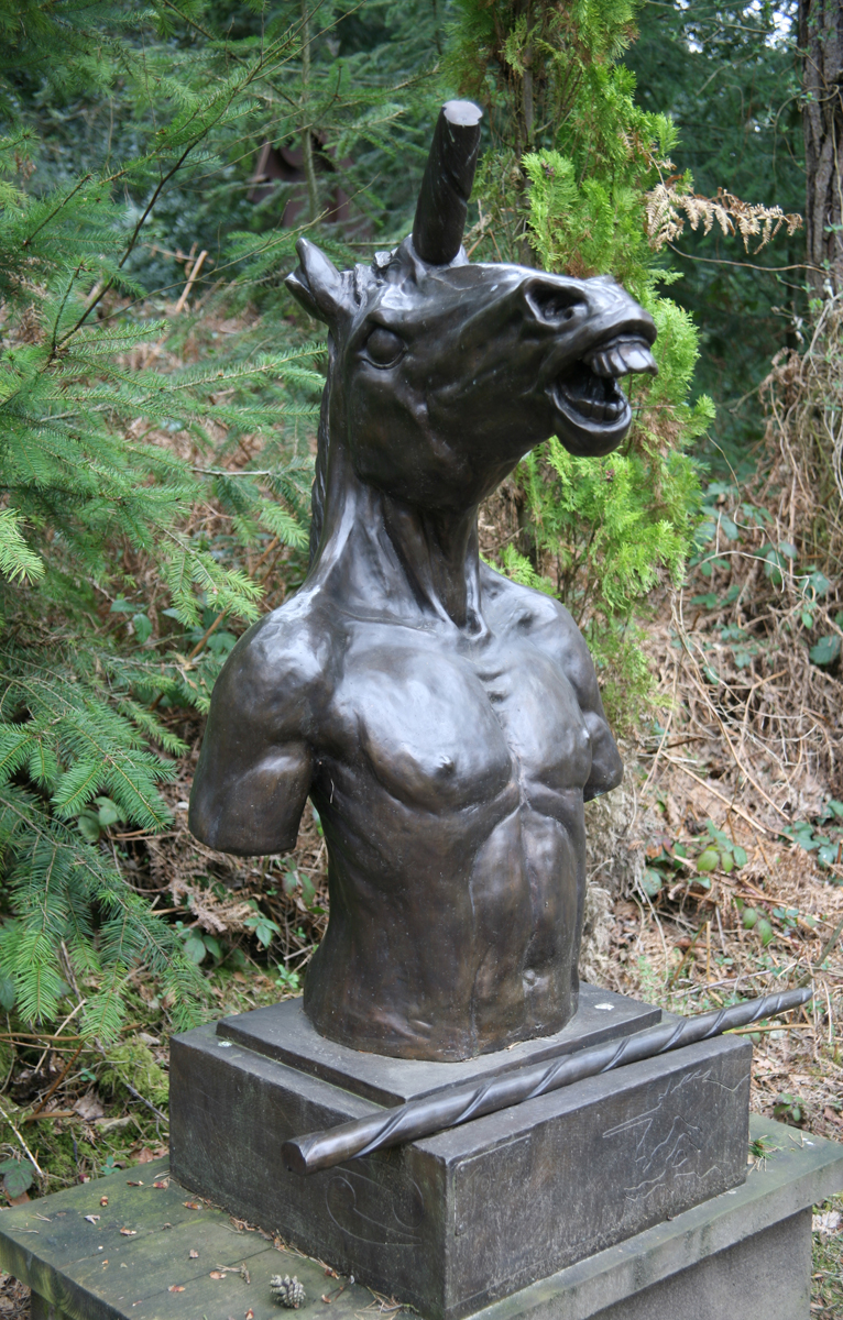 Bronze Figurative Sculpture of a Unicorn's Head on a Man's Torso. The Horn has been cut off and is resting in front of the piece