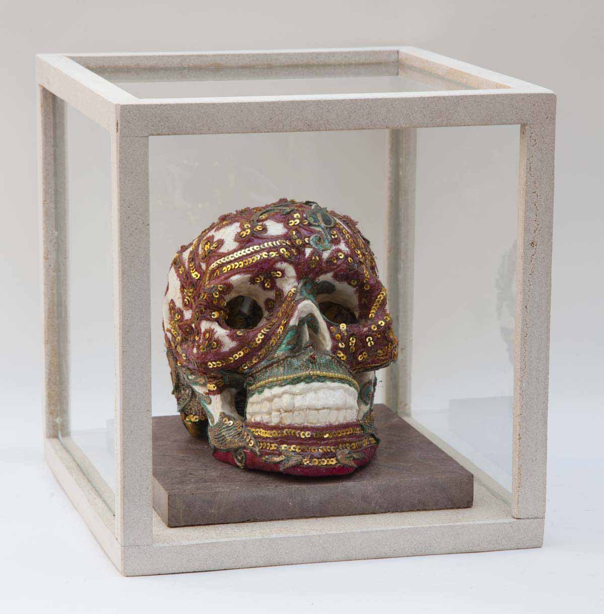 A abstract resin sculpture of a skull with red colours encased in a glass box.