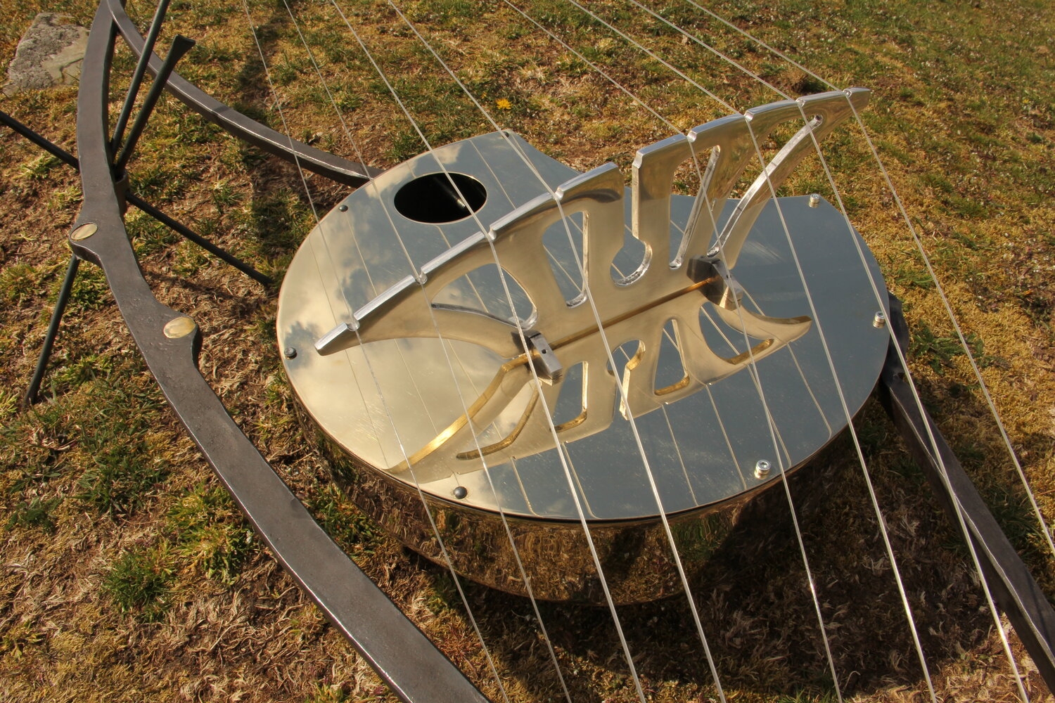 A abstract metal sculpture of a guitar mounted onto a stand.