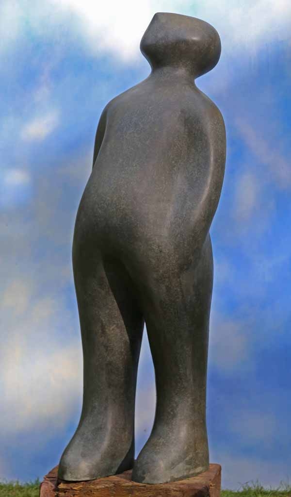 A figurative bronze sculpture of a figure standing and looking upwards.