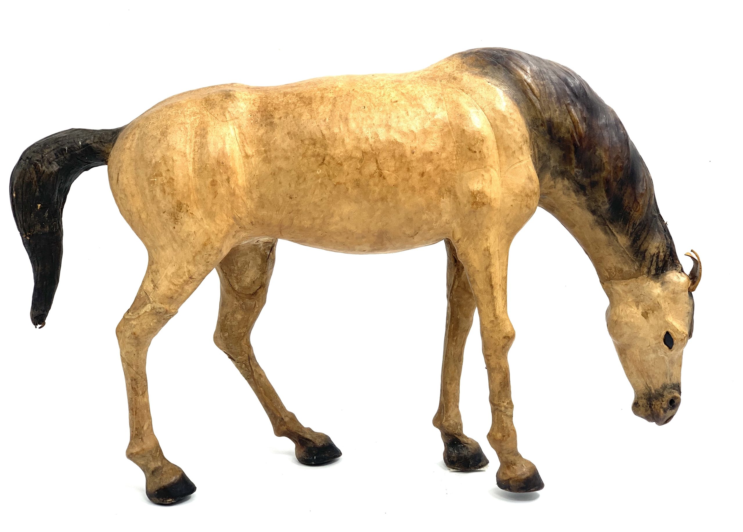 A realism figurative leather sculpture of a dun coloured horse with its head down.