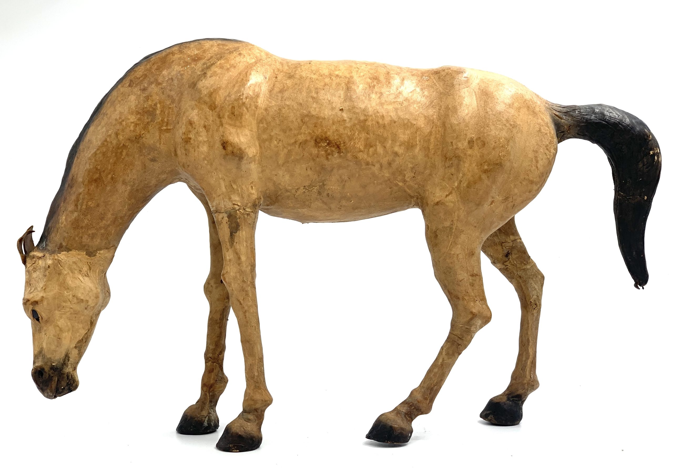 A realism figurative leather sculpture of a dun coloured horse with its head down.