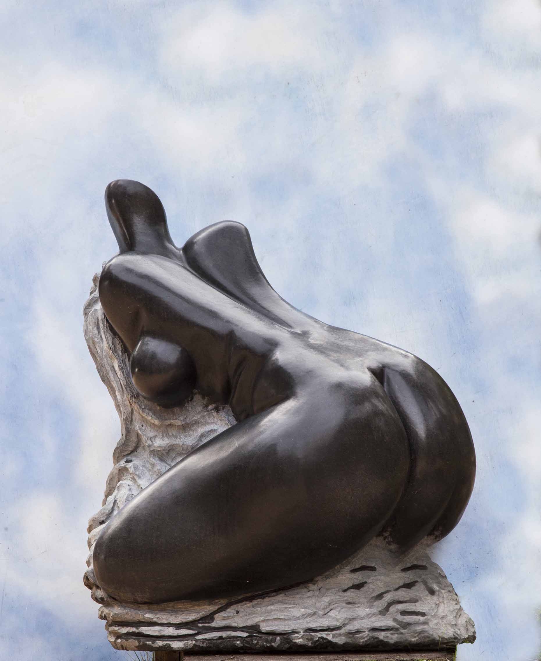 A shona stone sculpture of a woman's body leaning forward to expose her back.