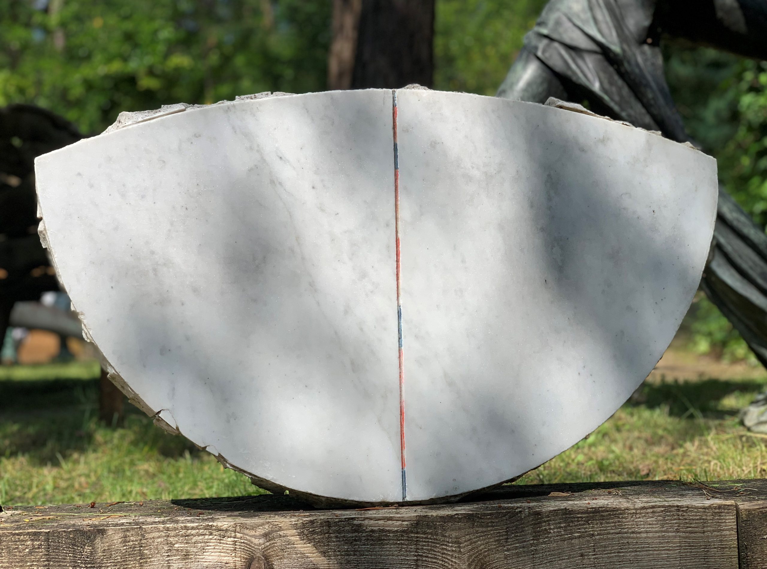 A abstract marble sculpture of a set of three different shapes all together.
