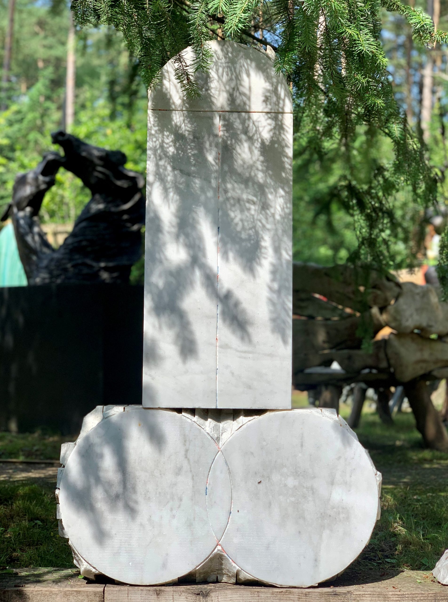 A abstract marble sculpture of a set of three different shapes all together.