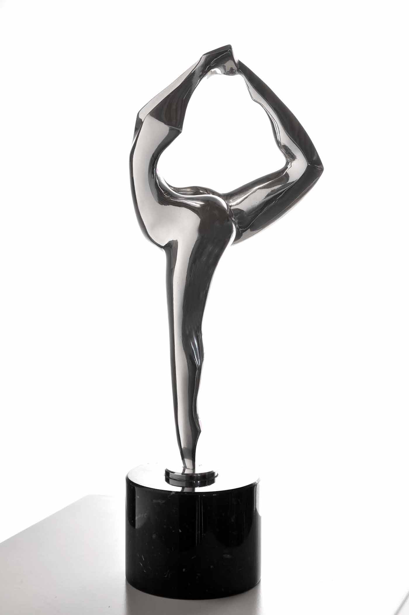 A figurative bronze and marble sculpture of a figure balancing on one foot with their leg raised to their head.