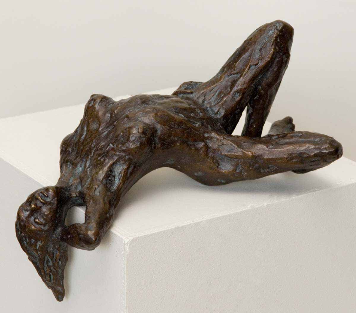 A figurative bronze sculpture of a woman lying down with her back arched.