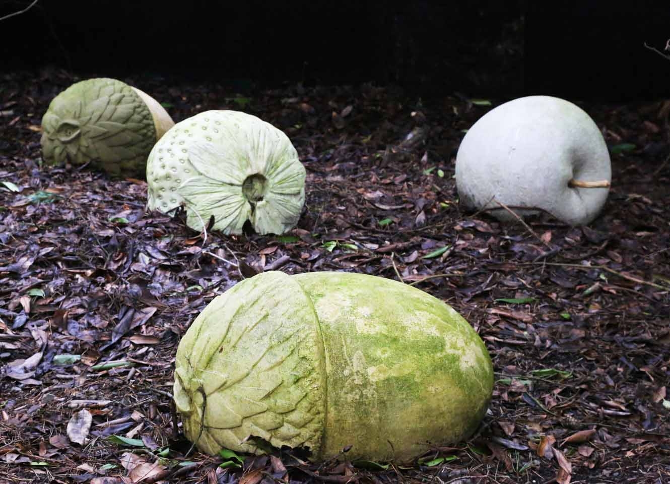 A realism stone sculpture of a collection of fruits, namely apples and pears.