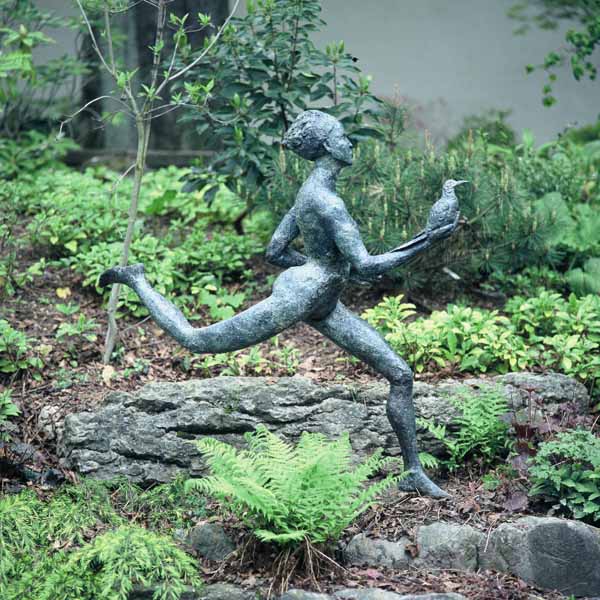 A figurative bronze sculpture of a person running while holding a bird in one hand.