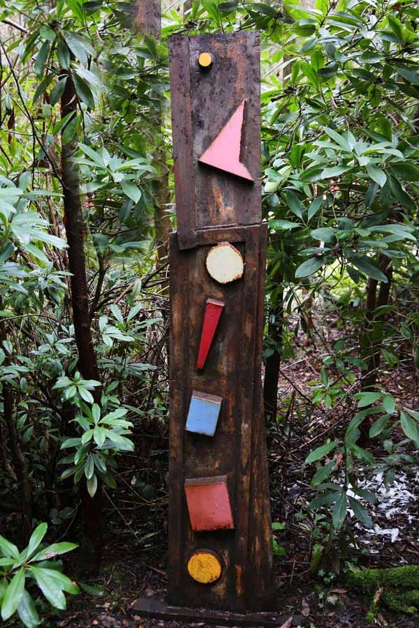 A abstract steel sculpture of a steel beam with various shapes on it.