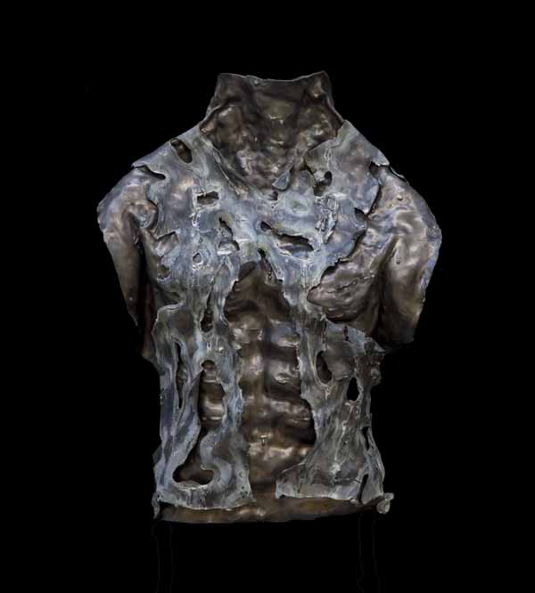A figurative lead sculpture of a male torso with ripped fabric covering it.