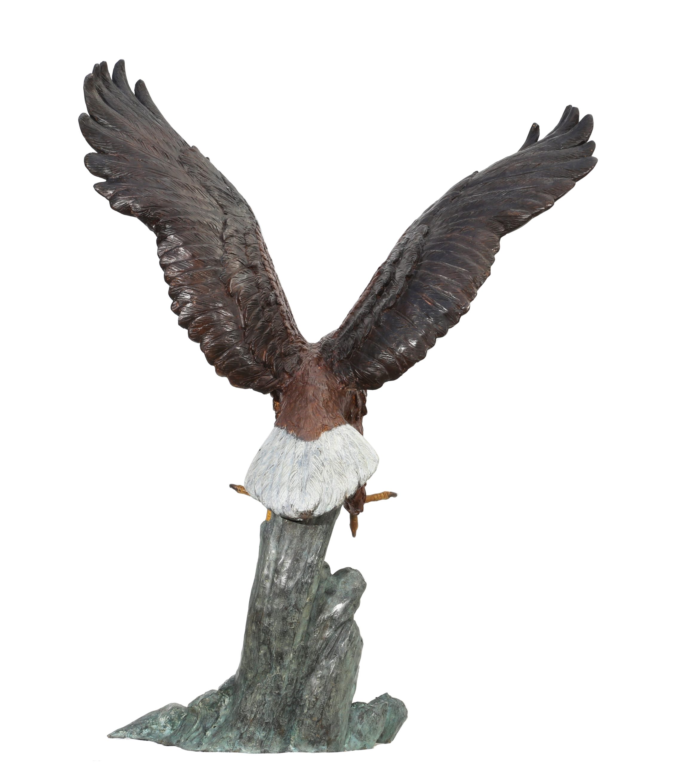 A figurative painted bronze sculpture of a bald eagle with its wings and talons outstretched, catching its prey.