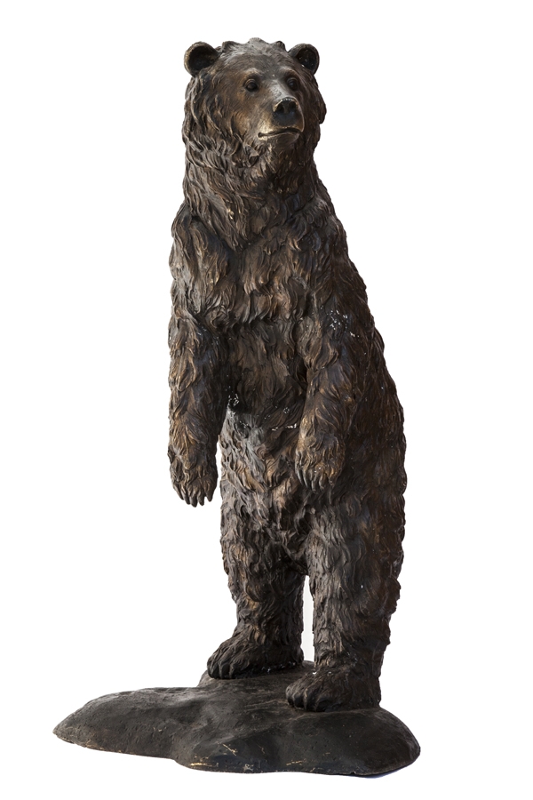 A figurative bronze sculpture of a life sized bear standing on its back legs and looking around.