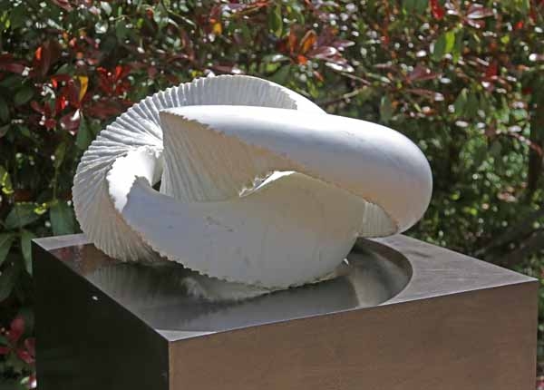 A abstract white marble sculpture of a curving yet ridged shape.