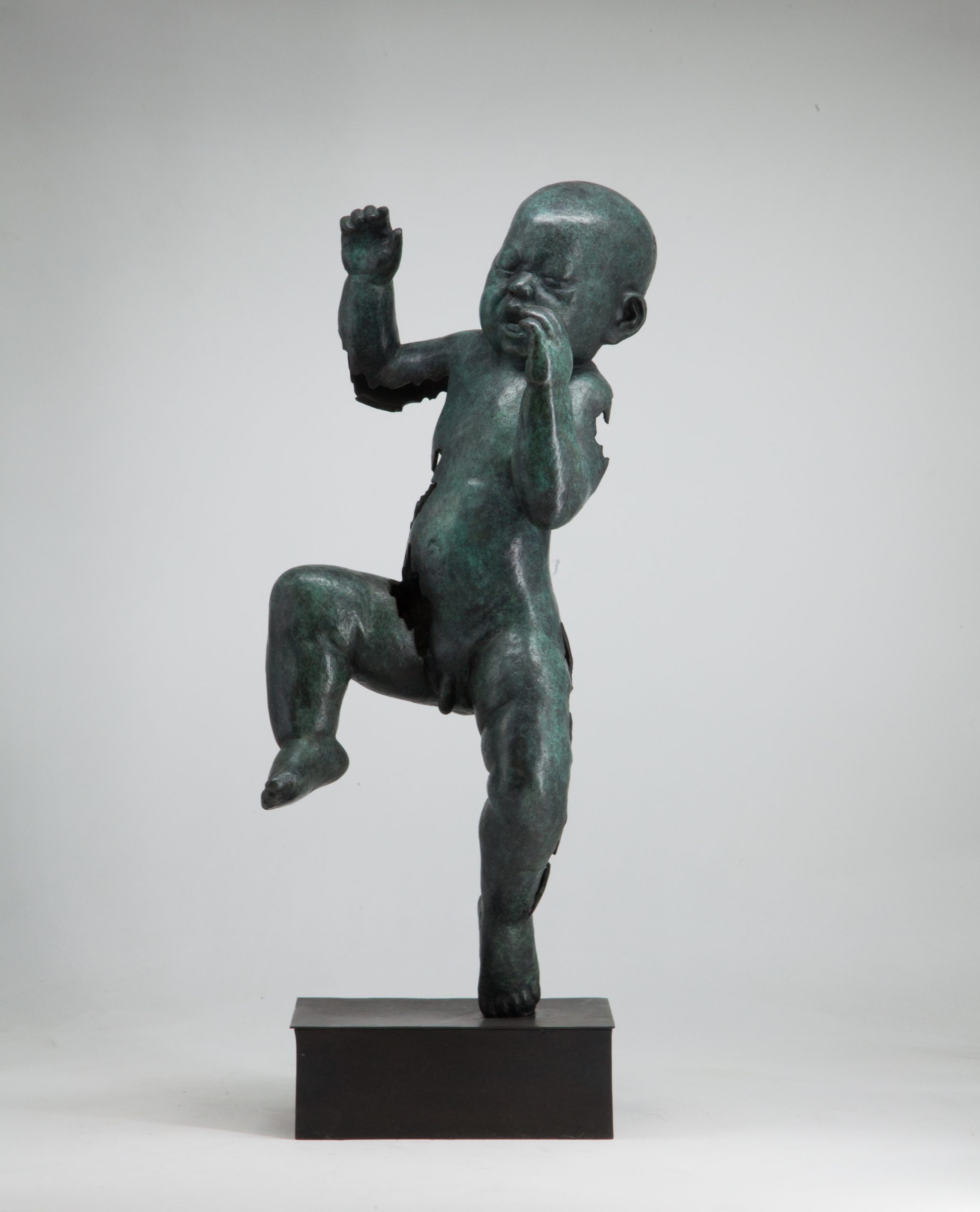 Figurative bronze sculpture of a newborn baby with both arms and one leg raised