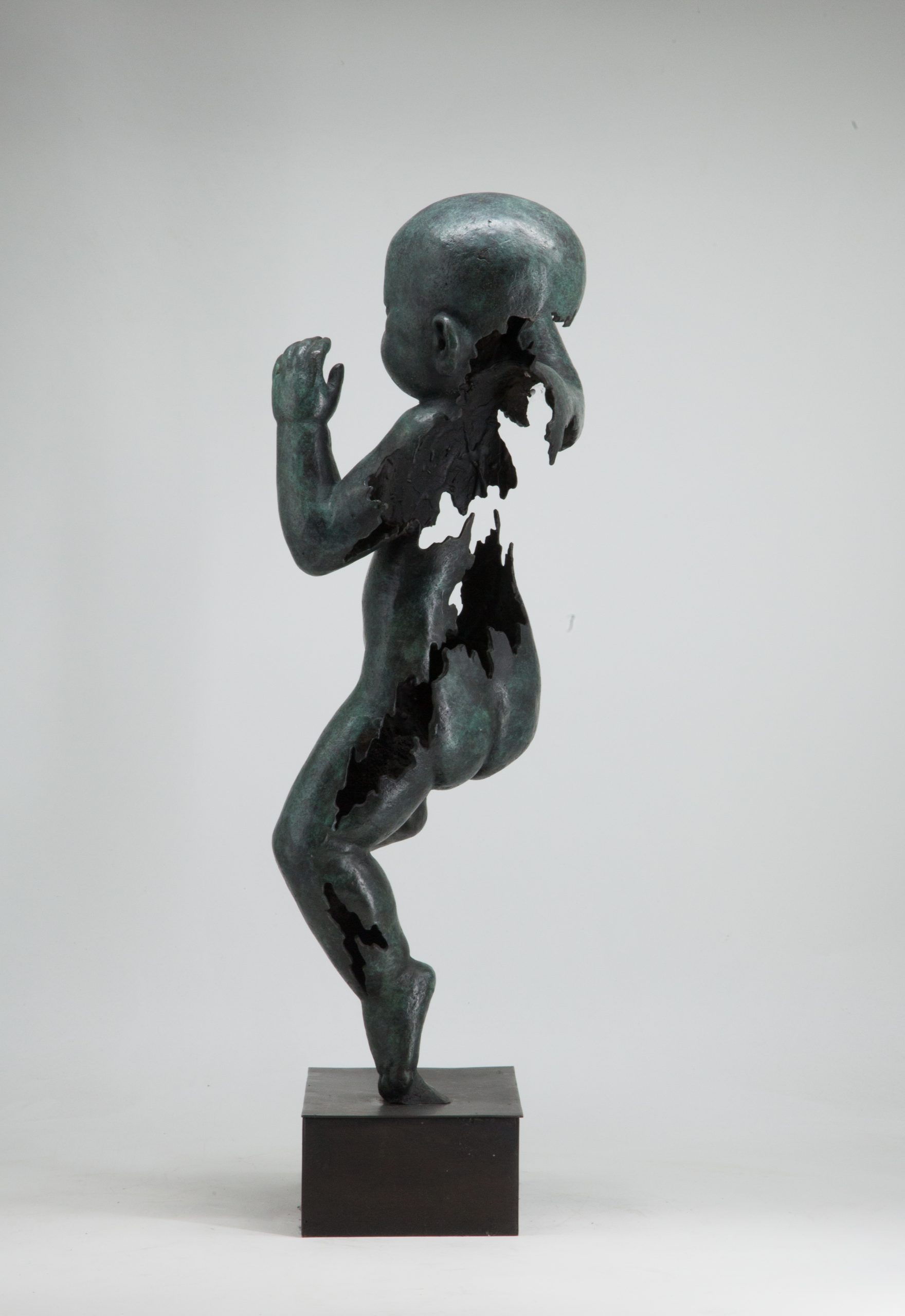 Figurative bronze sculpture of a newborn baby with both arms and one leg raised