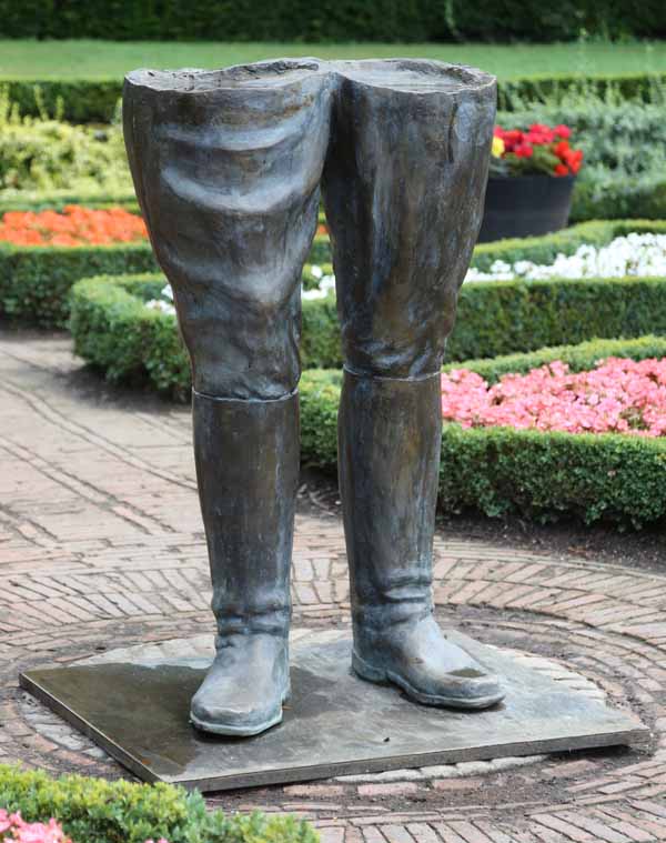 A figurative bronze resin sculpture of a pair of legs wearing boots.