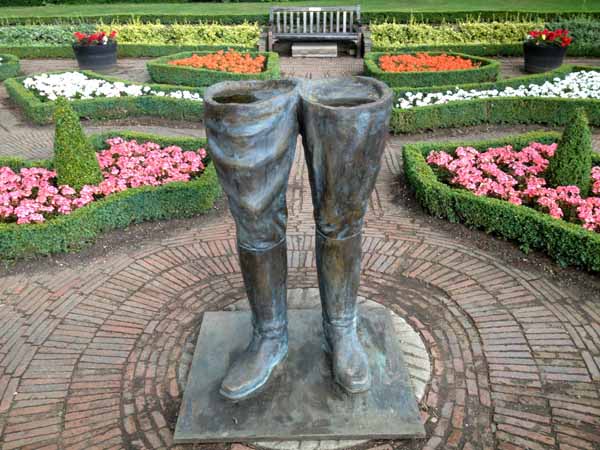 A figurative bronze resin sculpture of a pair of legs wearing boots.
