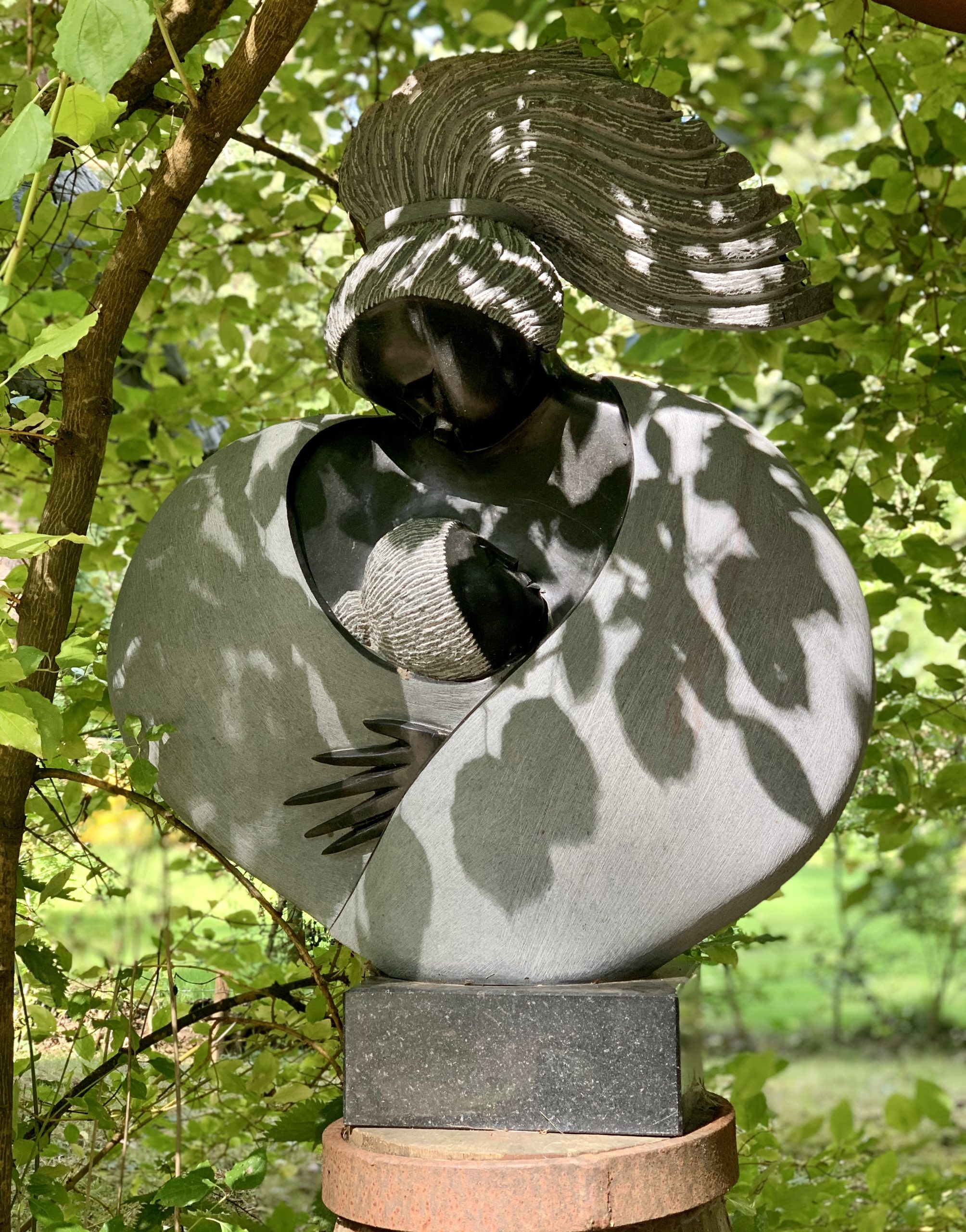 A shona springstone sculpture of a mother holding a baby.
