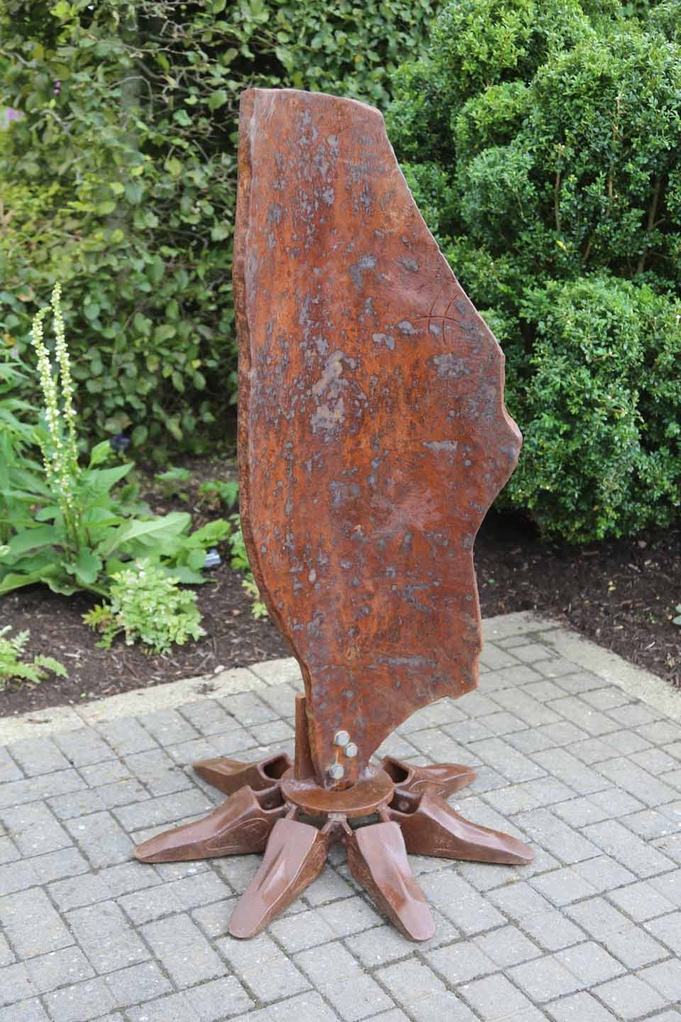 A abstract expressionism steel sculpture of a large sheet of metal bolted onto a stand.