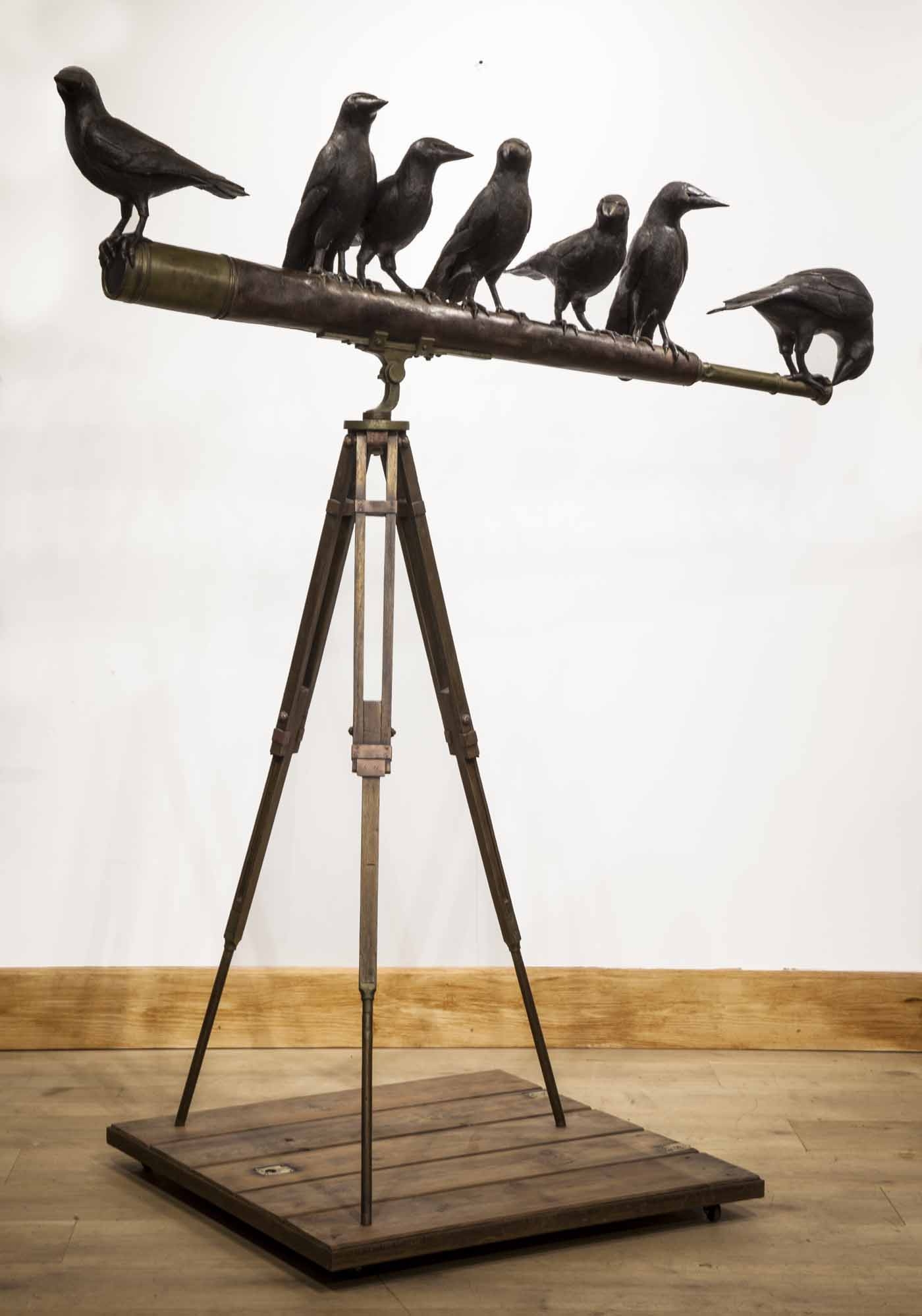 A sculpture of a telescope with seven crows perched upon it