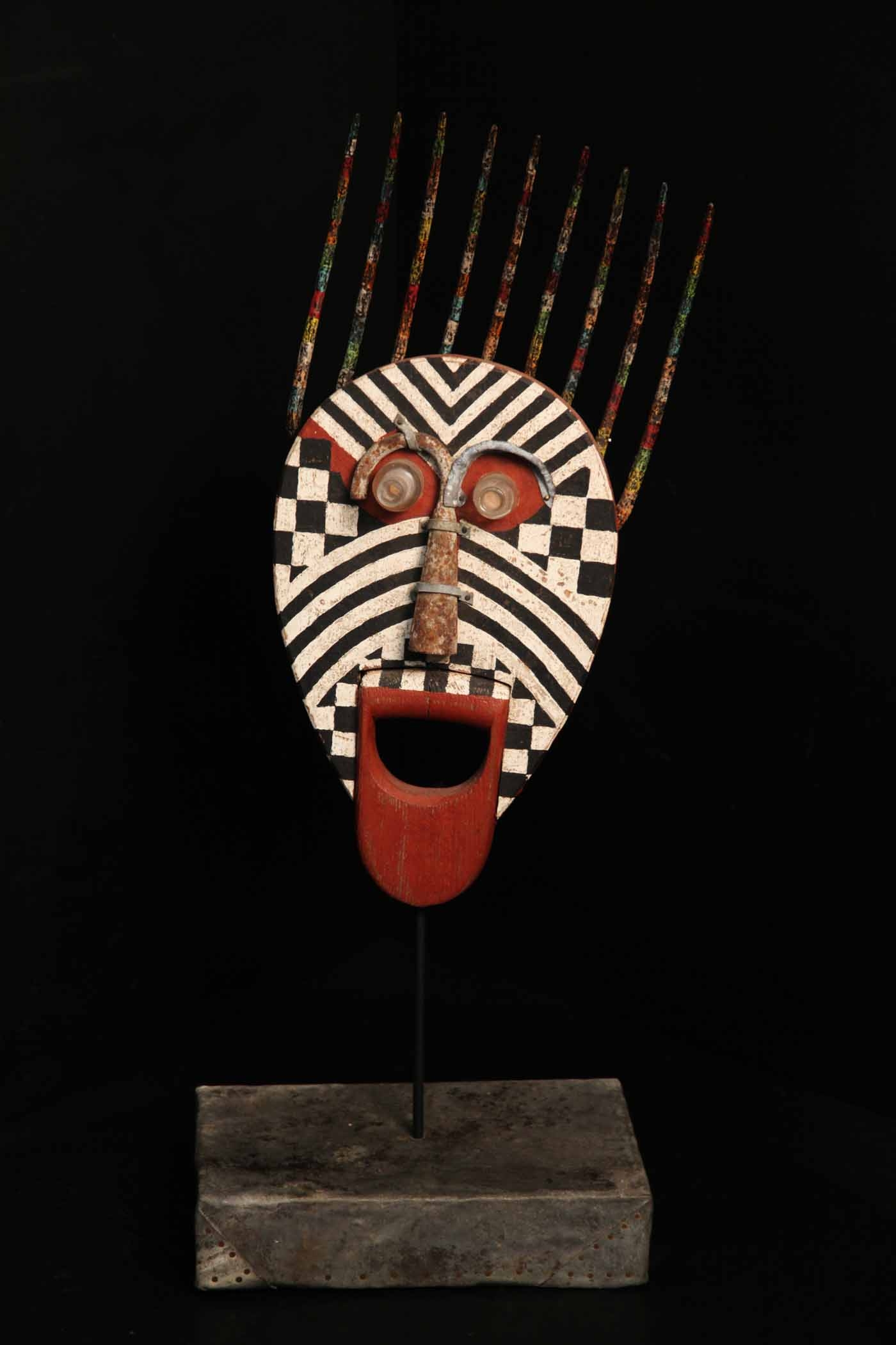 A tribal wooden sculpture of a mans face with red, white and black colours.