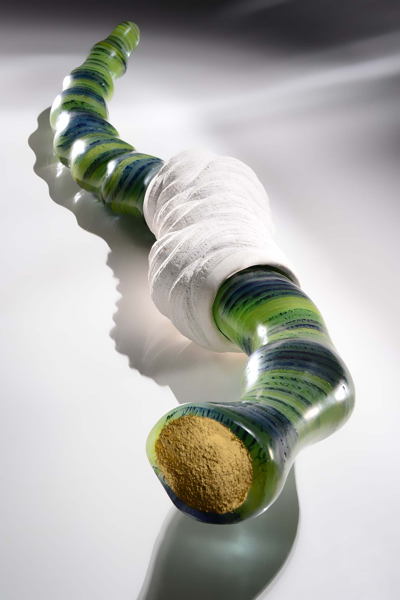 Green and gold leaf glass sculpture of a worm like creature in a cocoon
