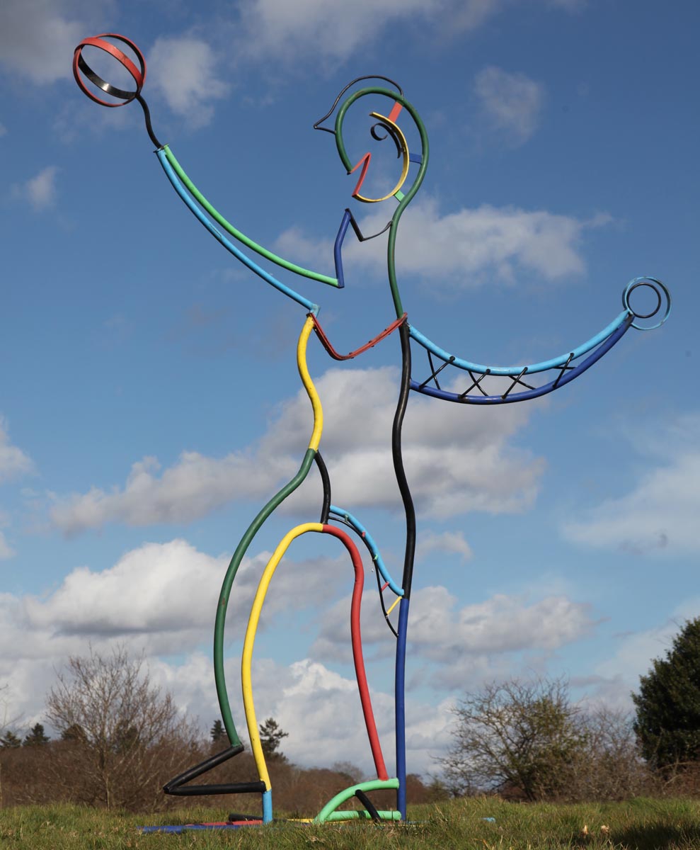 A pop art steel sculpture of an expressive figure made up of many colours standing.