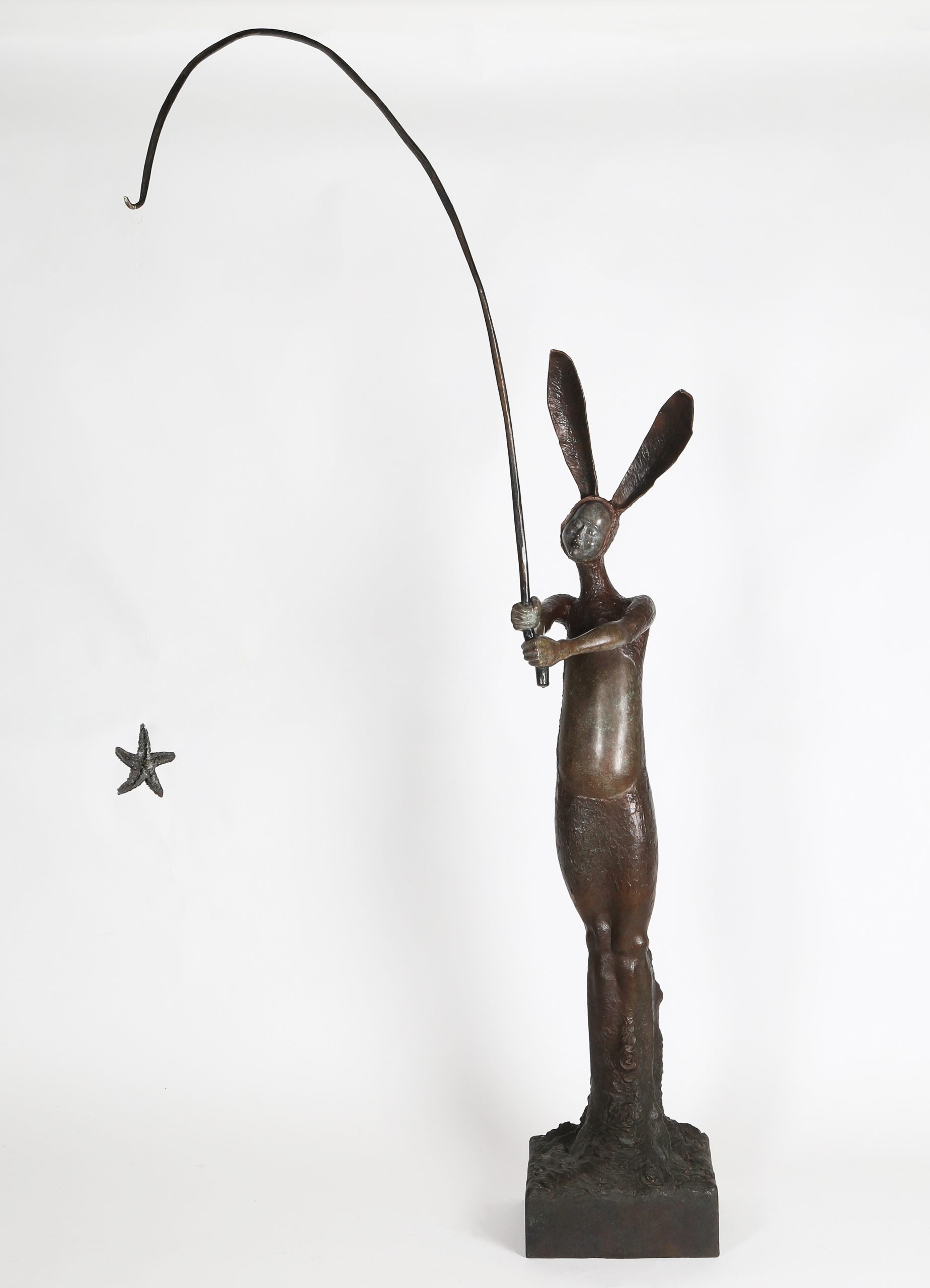 A figurative bronze sculpture of a person in a bunny outfit with a fishing rod.