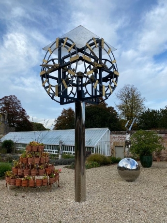 A monumental skeleton clock with gilt baton numerals and hands on an associated chromed steel column.