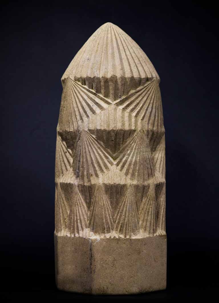 A architectural cotswolds stone sculpture of a tall tower with various patterns on the side.