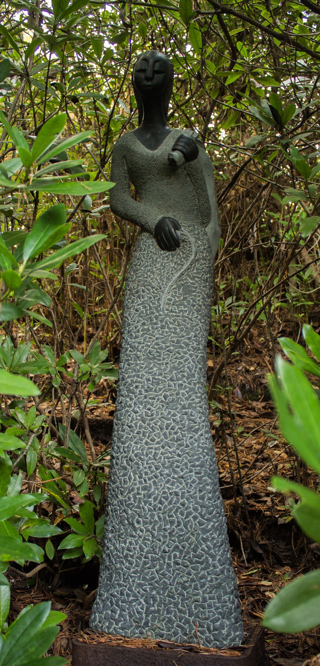 A shona stone sculpture of a persona carrying a bag over their shoulder.