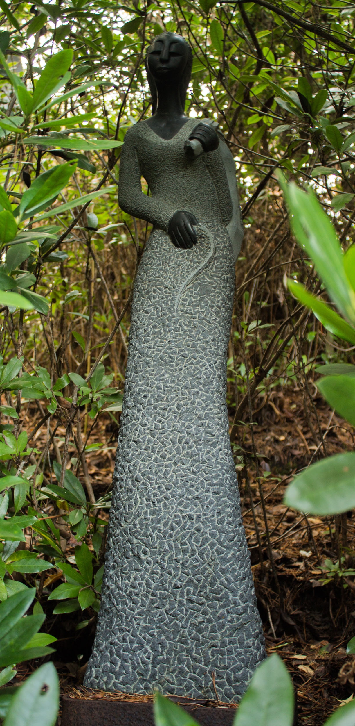 A shona stone sculpture of a persona carrying a bag over their shoulder.