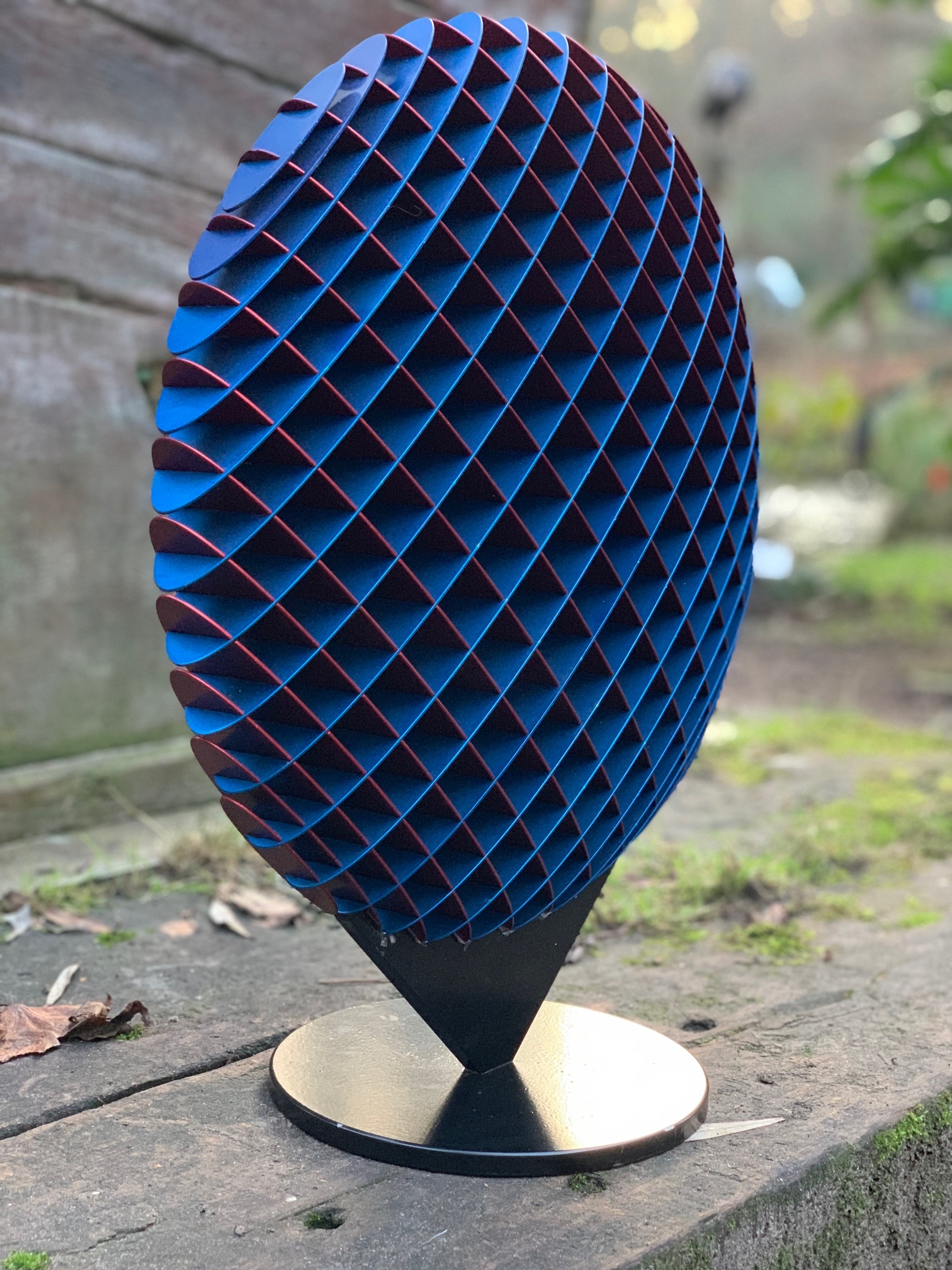 A abstract metal sculpture of a circle that changes colour depending on where it's viewed from.