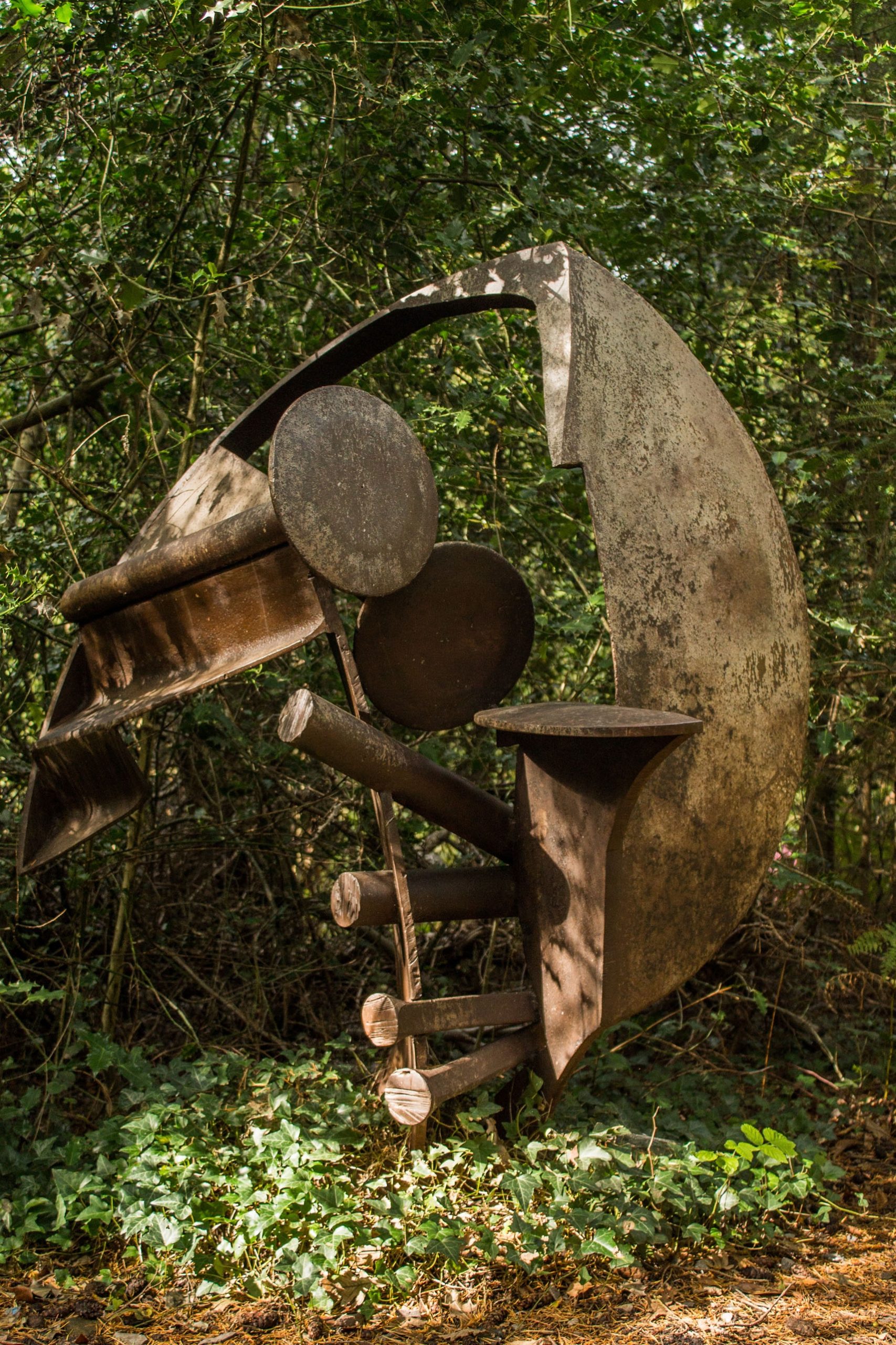 A abstract steel sculpture of various pieces of metal welded into a curved yet jagged shape.